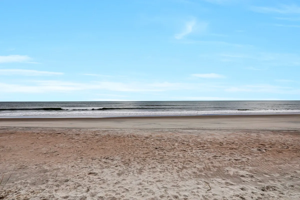 Another tranquil view of the beach, focusing on soft sand, ocean waves, and a wide sky. The open space invites playful exploration, relaxation, and shared moments by the sea.